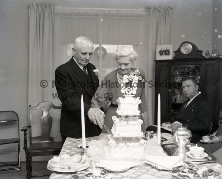 Tashiro, Dec. 26/54, Anniversary, Mr. Mrs. Geo. Vollett Mark 50th Anniversary, Mr. and Mrs. George Vollett, Well-known Portage citizens. Celebrated their 50th wedding anniversary Dec. 26. They are shown here cutting a cake made to mark the occasion 10664a.jpg