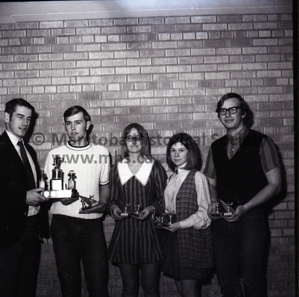 Moffat March 30/71 HS Curling
High School Curling
The Daily Graphic Trophy Presented
Grant Farncombe’s P.C.I. Rink won the Daily Graphic event in the Portage High School bonspiel. The event was open only to PCI and Arthur Meighen rinks. John Vopni on the left presents Grant with the trophy. On Grant’s left are second Susan Moorehouse, third Valerie Hrymak, and lead Clark Munroe. The Farncombe rink also won the Darragh Shoe event and the grand aggregate honors. The Darragh event was the bonspiel’s third event. For winning the grand aggregate the four above curlers received individual trophies from Delta Lanes. Farncombe and Jim Hicks were tied for grand aggregate honors, but Farncombe won a single game showdown.
1621b.jpg