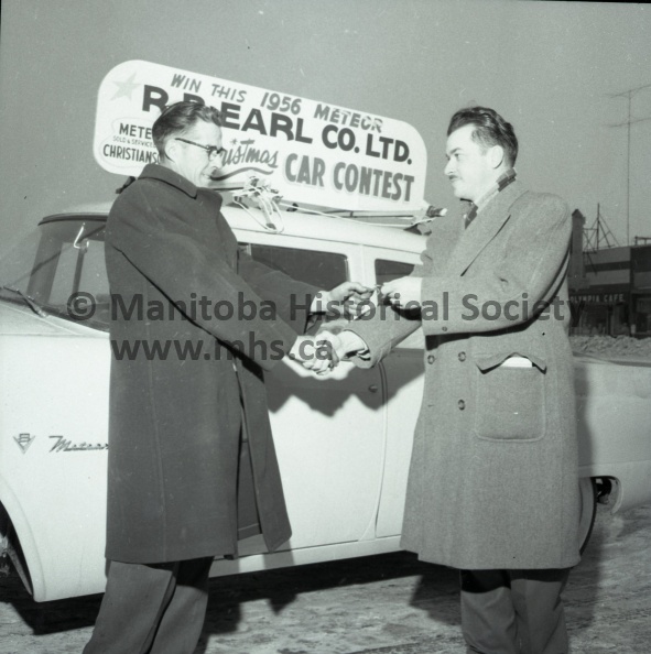 RAY HILL (left) smiles broadly as he officially receives the 1956 Meteor Car presented by R. B. Earl Co. Ltd. to the winner of the Christmas car contest. Mr. Hill held the second entry draw. Holder of the first choice of the three judges did not claim ownership of the car. R. B. Earl, proprietor of the store is shown above handing the car key to Mr. Hill. 10972a.jpg