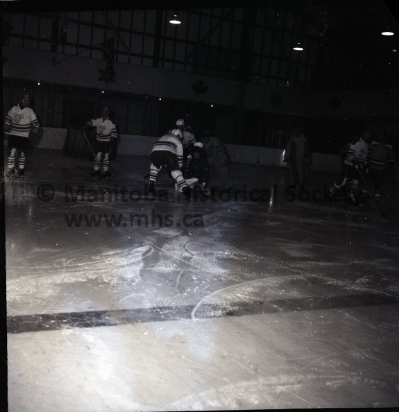 (Tashiro) March 16/69 Schmockey
Portage Minor Hockey Assoc.
2nd Annual Schmockey Nite
Pandemonium in the good-natured form broke loose during the third period of the second annual schmockey game Sunday night at the Centennial Arena between Liniment League All-Stars and the Portage Minor Hockey Association coaches. Here, the Minor League group led by Pokey Blight and Moe Cartmana, throw the referee over the boards after they had decided they could get along better without game officials.
Easy way out is in the mind of Gerald Cobbe, MP, one of the gritty gladiators of the broomball game held in the Centennial Arena as part of the second annual Schmockey Night. Carting him off are his opponents, the burly firefighters, who out-muscled the lighter challengers comprised of city officials, press and radio, and the mayor. 11214i.jpg