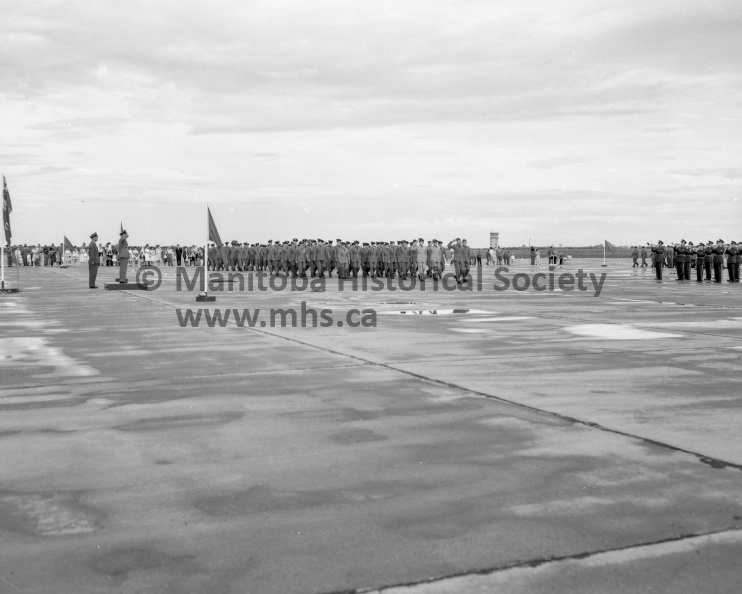 Photographer: Tashiro
July 21, 1961
Southport
Golden Hawk Show - Wings parade combine
March past - At top, GC J. R. Frizzle, Ieft, Commanding Officer of RCAF station Portage, takes the salute during a march past which concluded a wings parade ceremony at the base Friday night. At bottom the Red Knight makes a sweep of the station during the aerobatic show which followed the graduation ceremony. Some 4,000 people were on the station to witness the display. VP-1-01174-013.jpg
