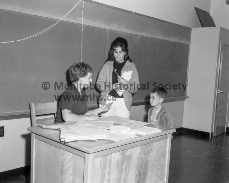 Photographer: Tashiro
September 3, 1963
Educational
School terms open - City schools bulging
First day of school: An entire new life was opened to an estimated 300 city youngsters this morning as school opened for another term. The youngster above were apprehensive and made certain his mother came along to help him get started. This is only one of the many mothers and fathers who were helping enrol beginners this morning. This scene was at Fort la Reine school but was repeated in all other city schools. VP-1-00105-001.jpg
