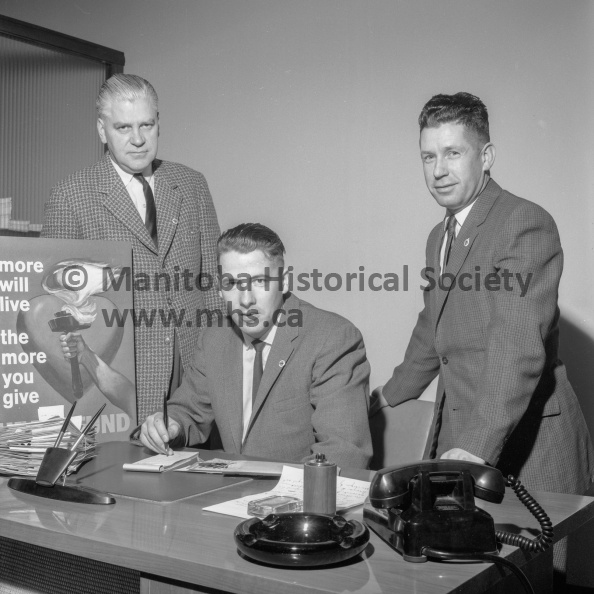 Photographer: Tashiro
February 28, 1963
Heart Foundation
Heart Foundation blitz headquarters
Checking returns Thursday night of the Heart Fund canvass in Portage is Don Cooper, centre, accountant at the Bank of Montreal branch here. Looking on are co-chairmen Ald. W. H. Vopni, left, and Stan Antonissen. Early reports showed about $1,300 returned with more still to be turned in. A final accounting is expected by Wednesday. VP-1-00665-001.jpg
