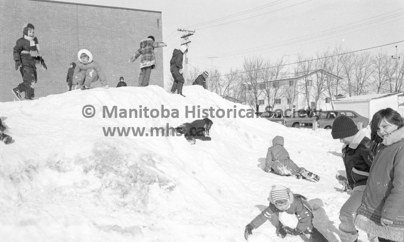 Photographer: Tashiro
February 18, 1975
Winter Weather
Comfortable moderate temperatures return to forecast
Playing in comfort
Comfortable moderate temperatures have returned to the forecast region allowing children to have a rollicking good time outdoors. Due to a fairly heavy accumulation of snow this winter, there are all kinds of high mounds for youngsters to slide on. However, there is one warning. Make sure the mounds are far enough away from traffic flows. Motorists, too, must be on a constant look-out for hazardous situations. VP-2-00185-001.jpg
